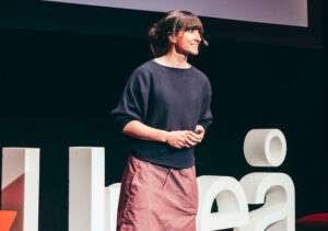 Johanna står på en scen och föreläser på Ted Talk